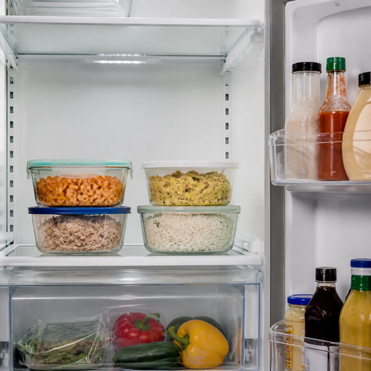 Realistic editorial photo of clear containers of leftovers placed on a middle refrigerator shelf, fridge door shelves vi