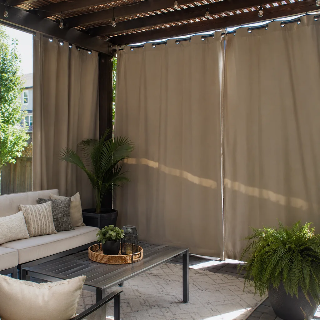 Realistic editorial photo of an outdoor patio with pergola curtains, seating, plants, fabric panels, and sunlight showing heavy drapes blocking daylight